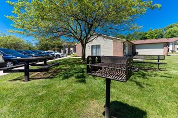 A grill and picnic table in the grass in front of a house